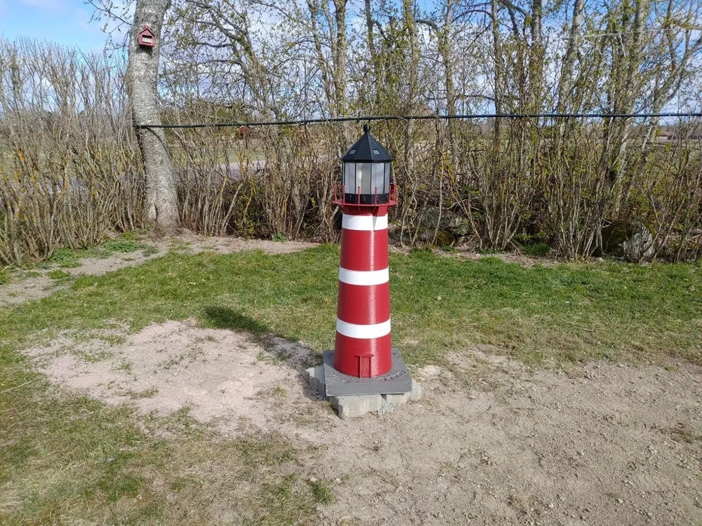 Tall red and white printed lighthouse installed outdoors